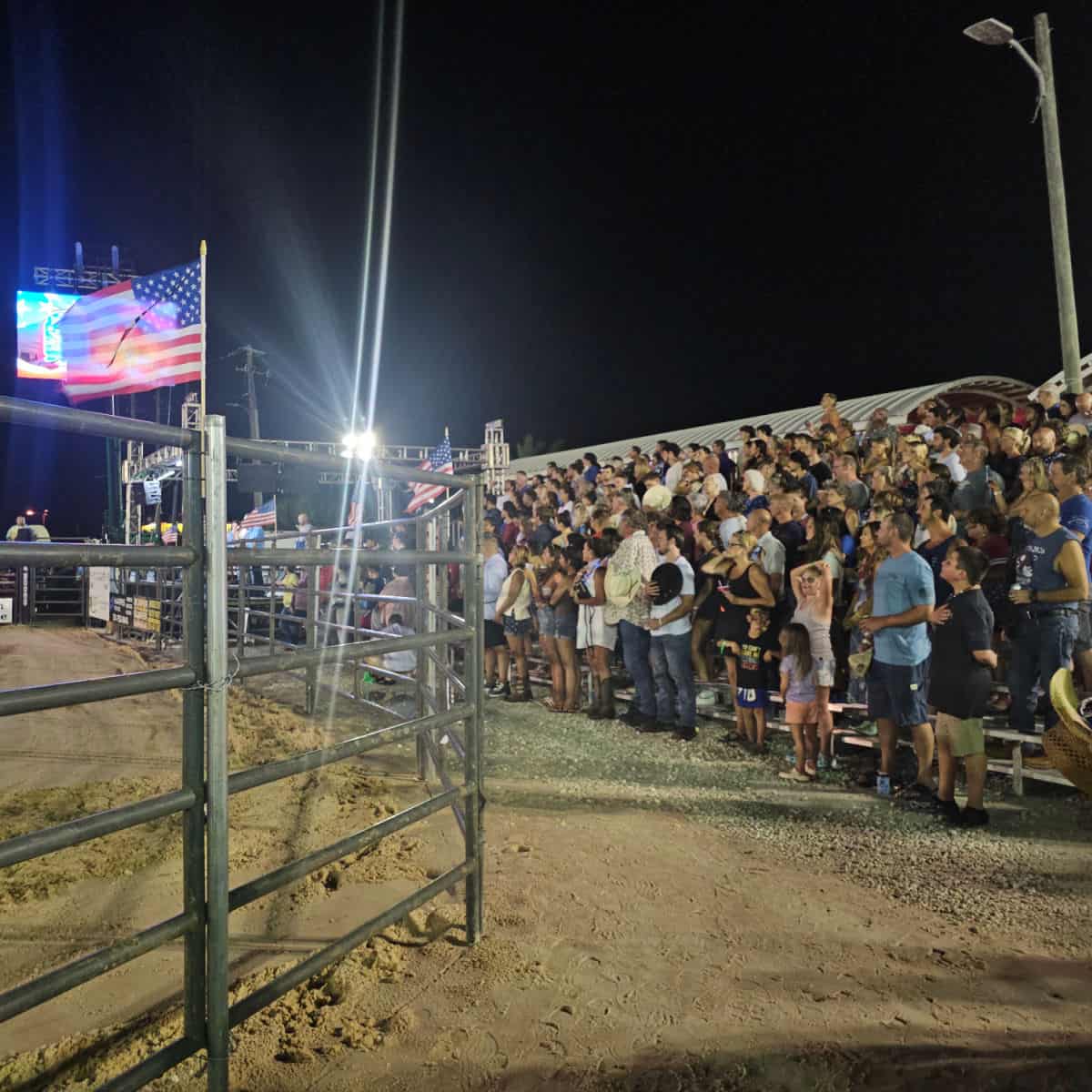 American Flag above the rodeo ring with bleachers around the outer edge fille with people