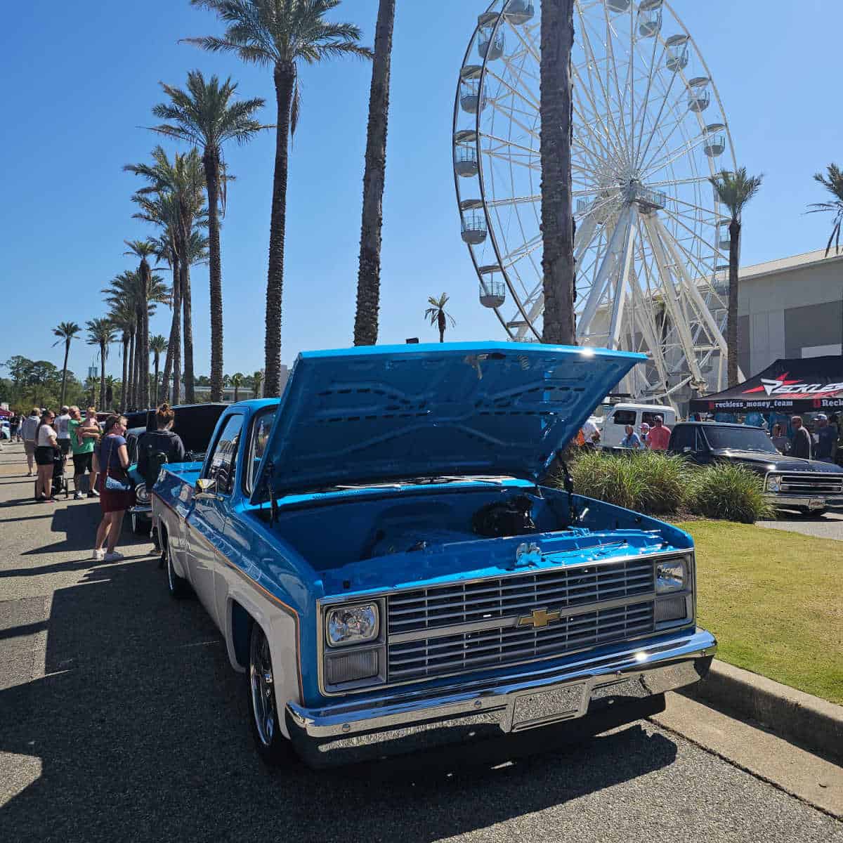 Blue Truck with the lid open on the main street at The Wharf with the ferris wheel and palm trees in the background
