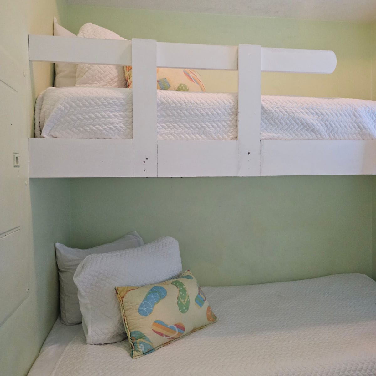 Bunkbeds with white linens and tropical flip flop pillows on them