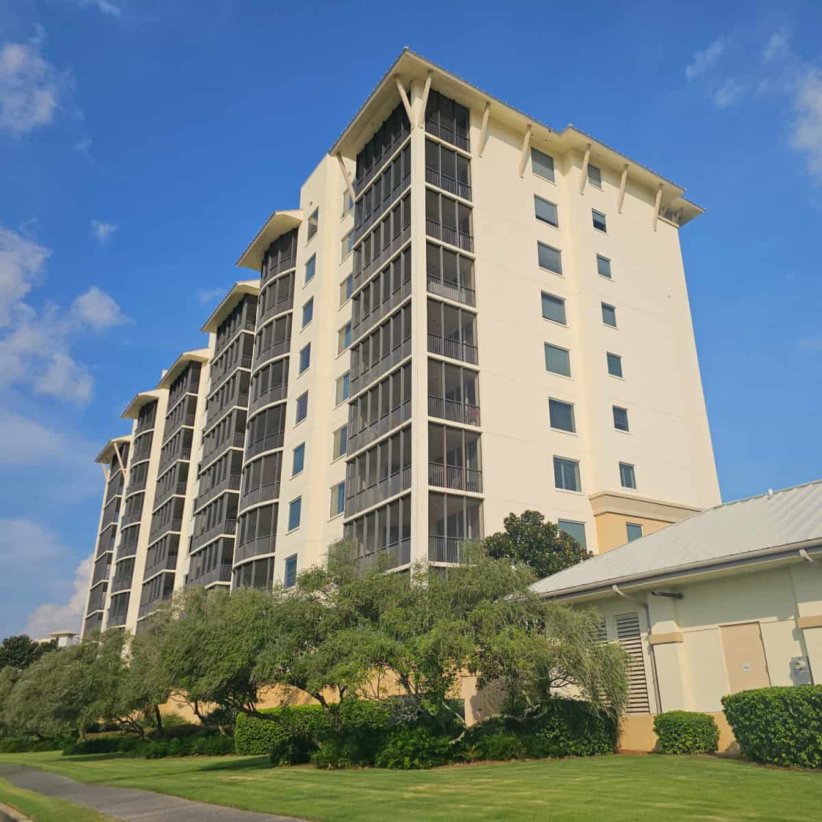 Tall condo building with trees below it on a sunny day 