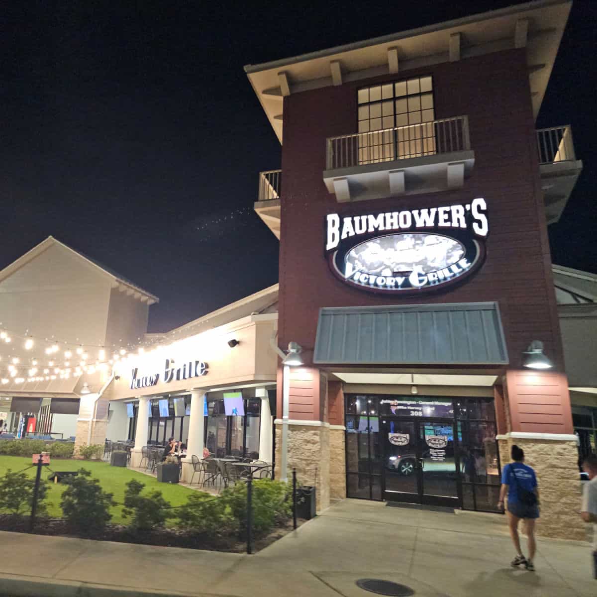 Baumhowers Victory Grille Sign over the entrance to the restaurant wtih lights and walkway