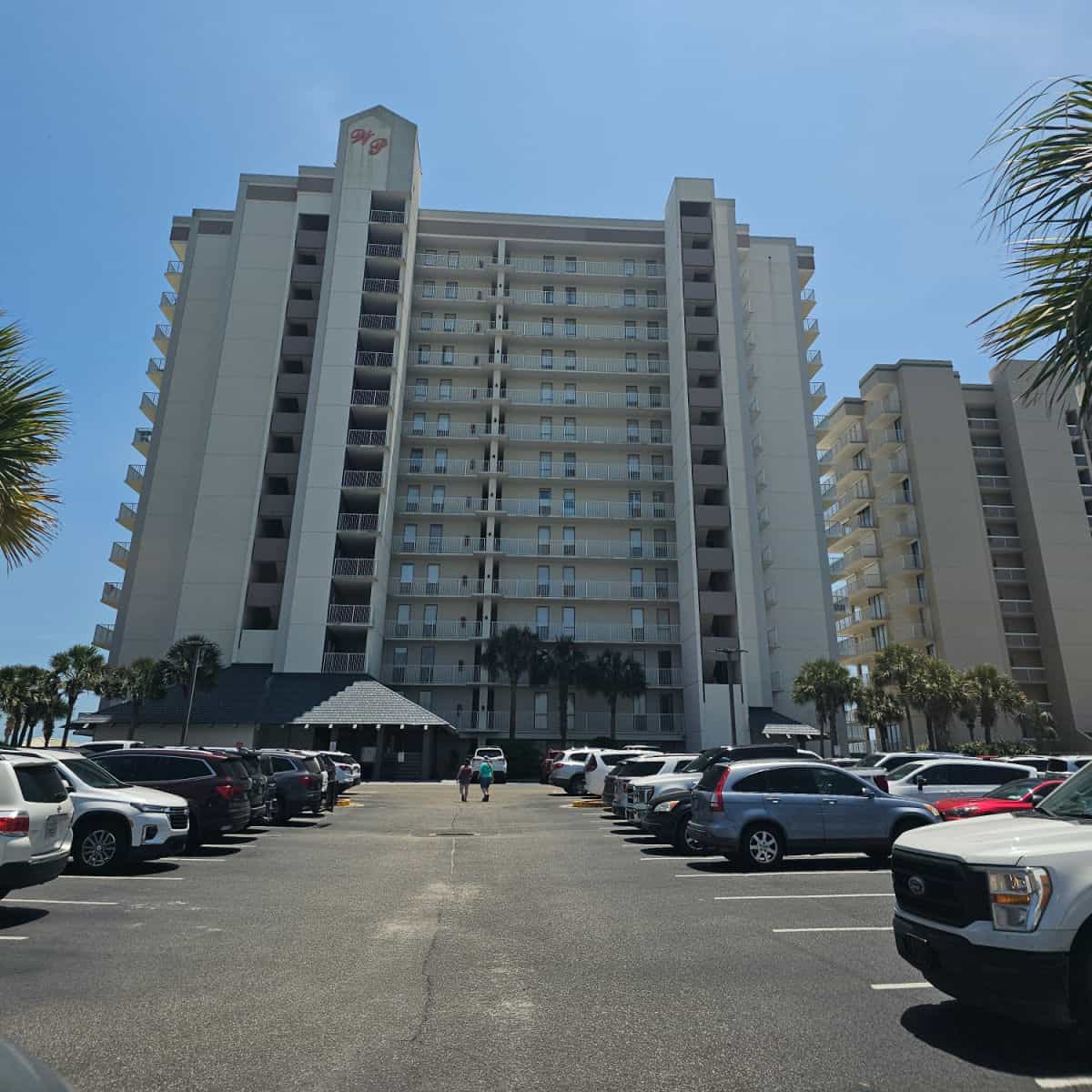 Looking across a parking lot to Windward Pointe condo building with palm trees on the edge of the parking lot