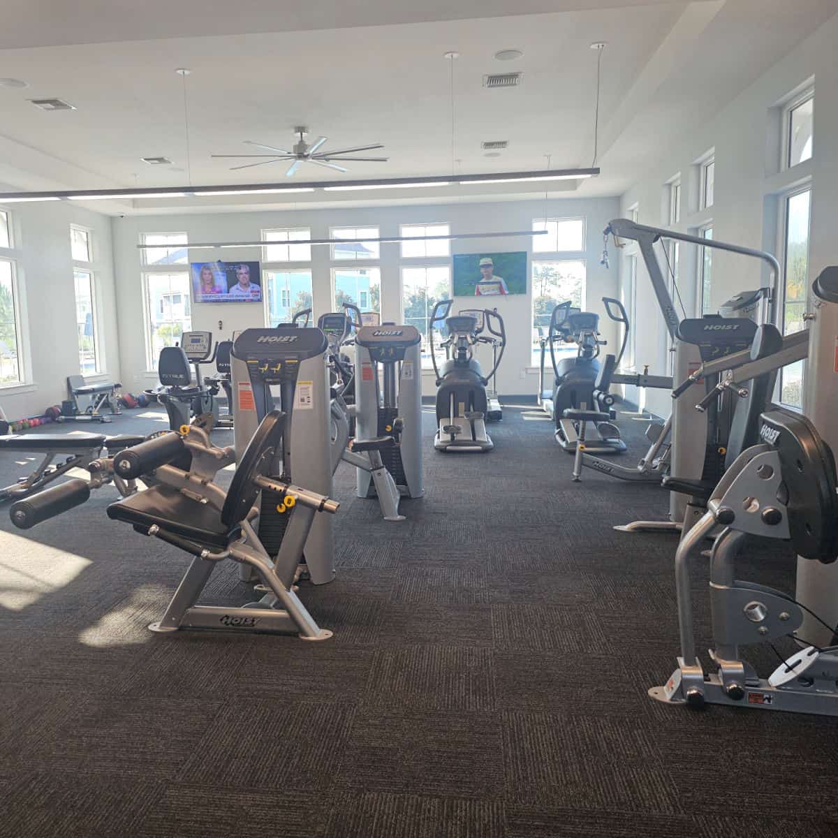 Fitness center with exercise equipment and tvs on the wall
