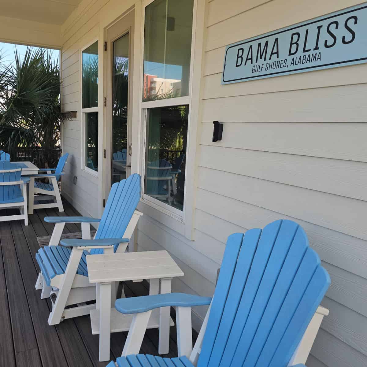 Bama Bliss Gulf Shores Alabama Blue sign on the side of the white cottage with blue and white Adirondack chairs on the deck