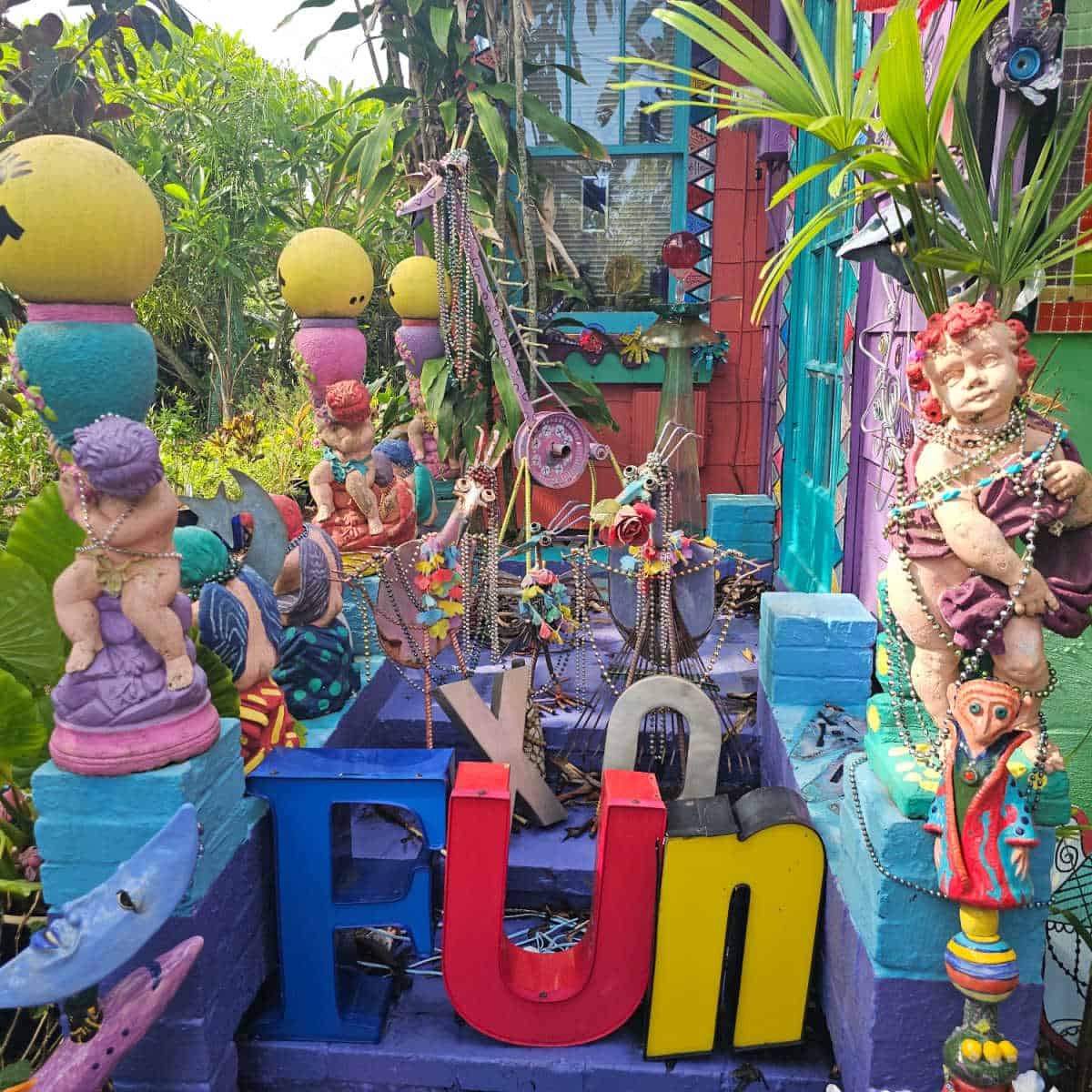 Fun and XO letters in between colorful dolls and metal birds on the steps of a colorful house