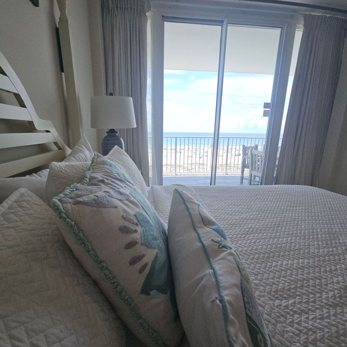 White linen covered bed looking out towards the beach and balcony