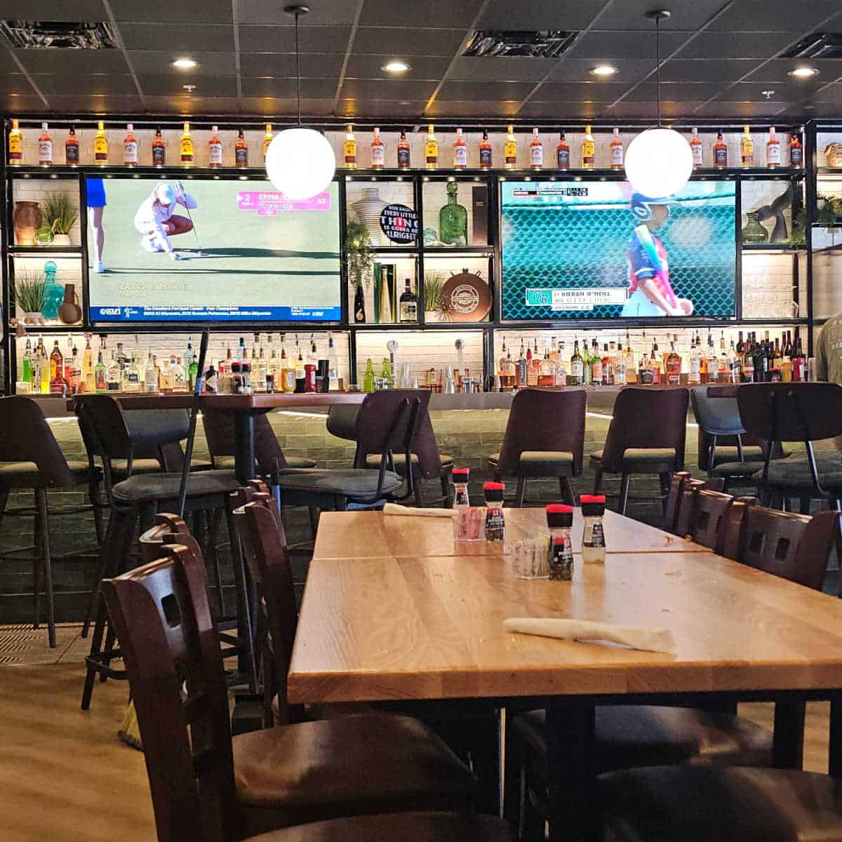 Indoor bar and tables at Old Salt Tavern with two large flatscreen tv's surrounded by bottles