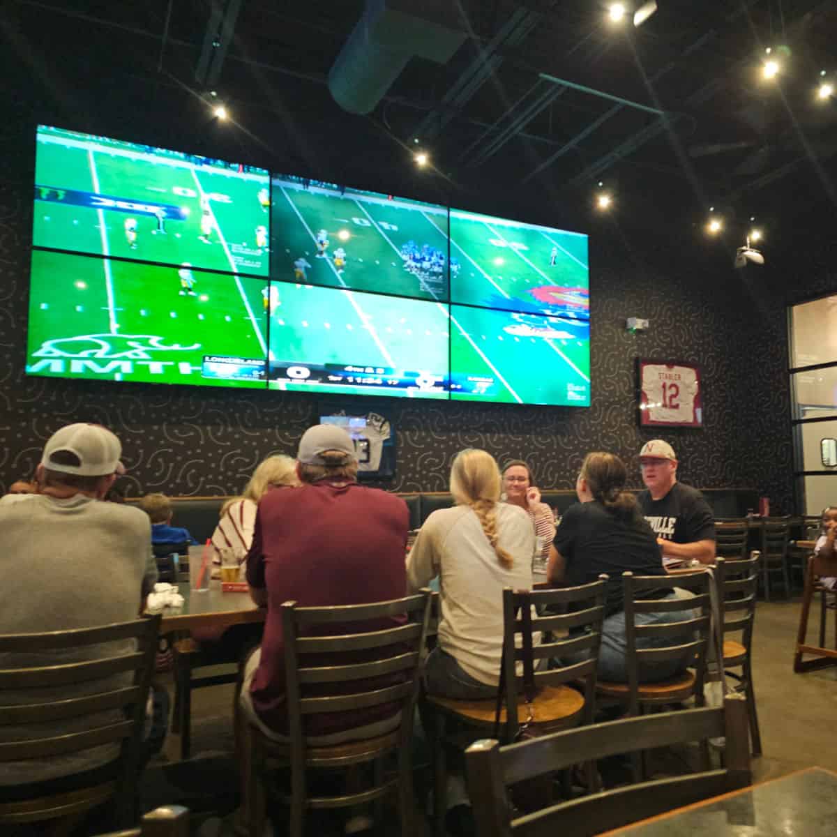 giant tv screen playing football above a long table in Baumhowers, football jersey on the wall