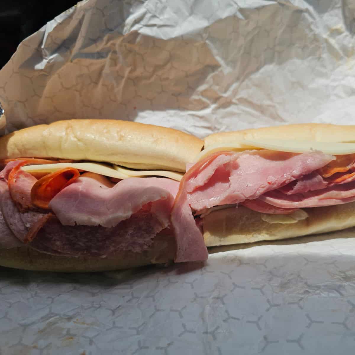 Italian sub with lots of meat sitting in a foil wrapper