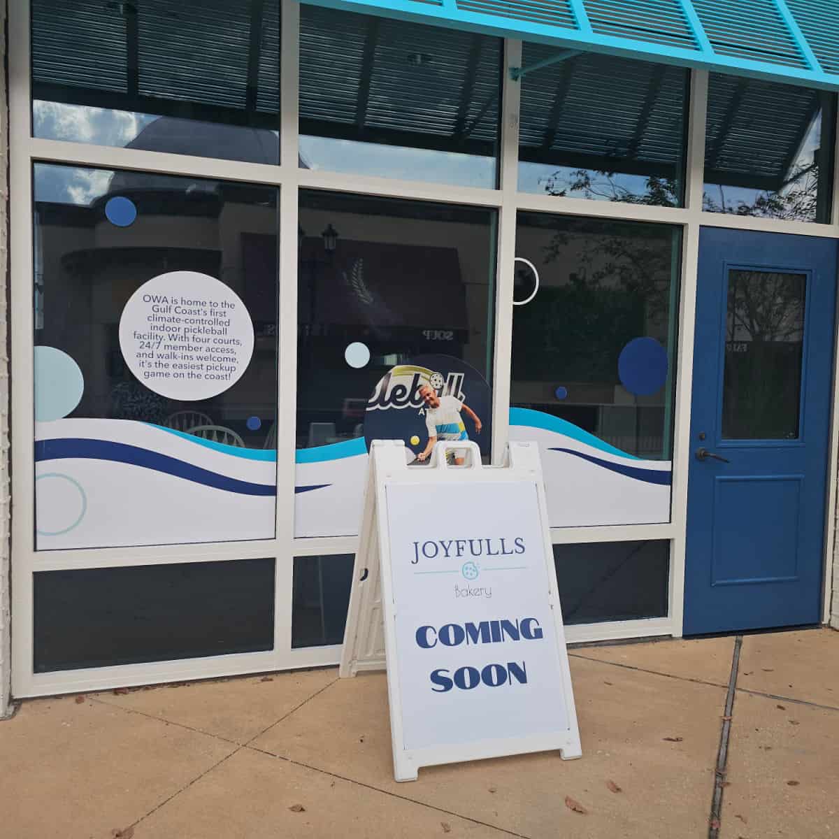 Joyfulls Bakery coming soon sign in front of a glass window and entrance door to the store