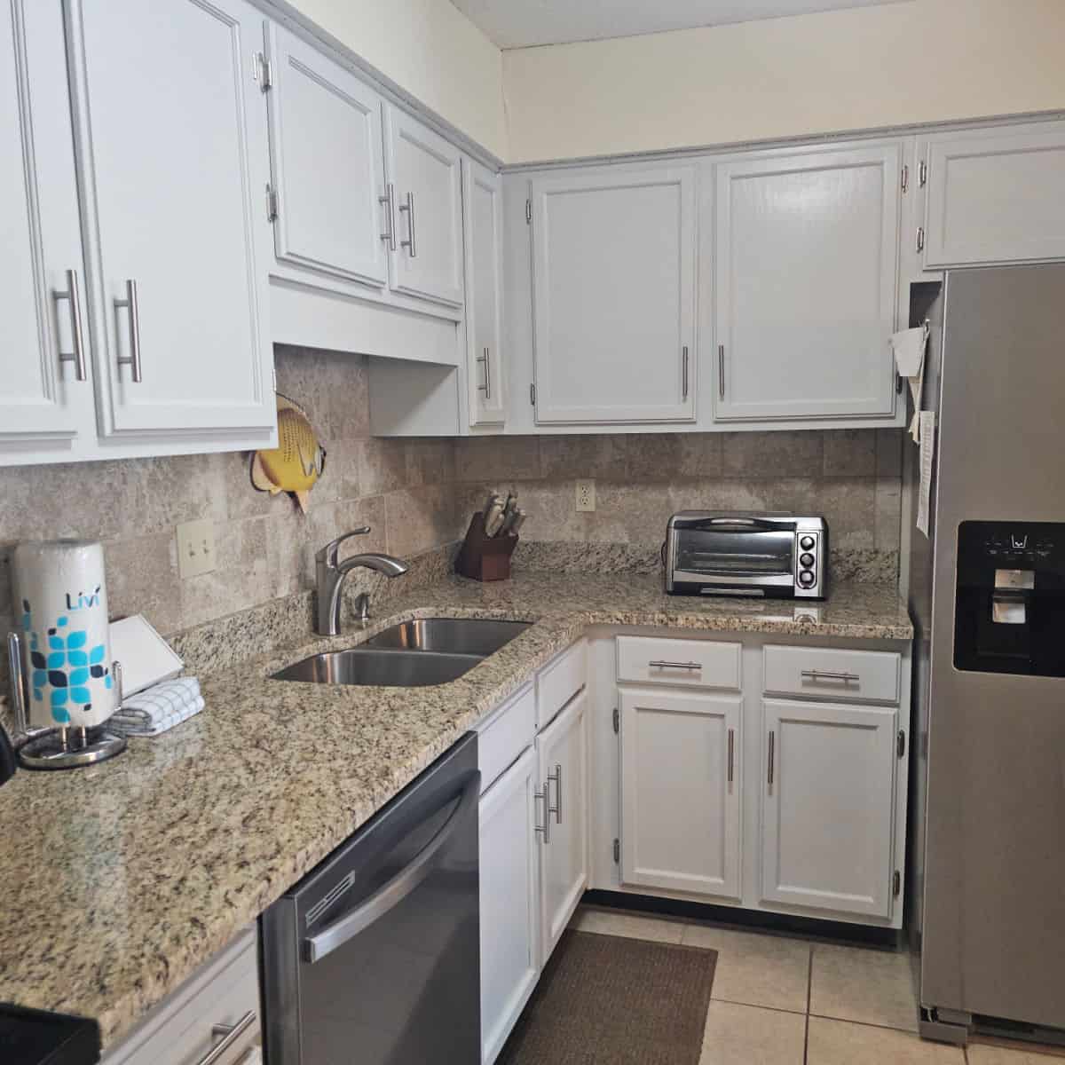 kitchen with white cabinets, stainless steel appliances, and brown and tan counter