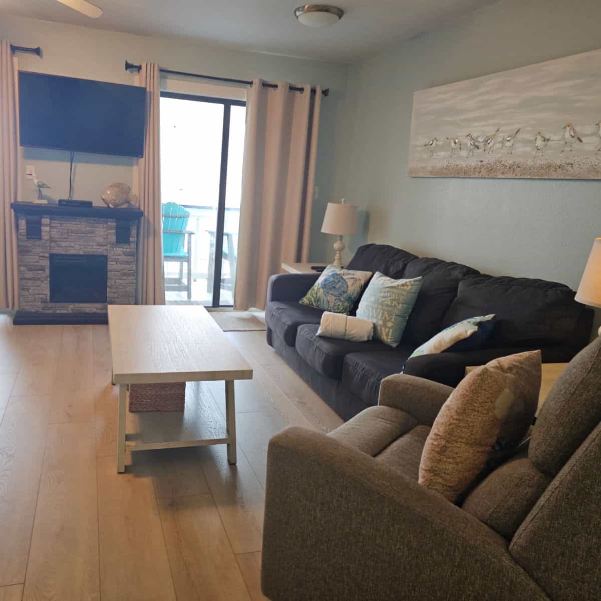 looking over two couches towards the balcony and fireplace and tv on the far wall.