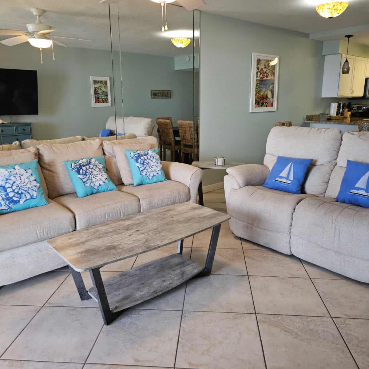 Living room with two couches, coastal cushions and a wooden table, mirrored wall