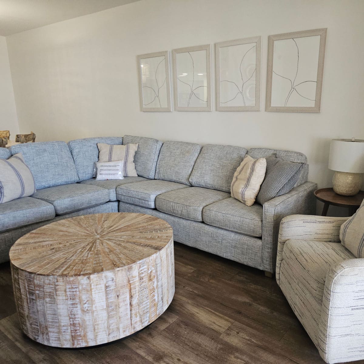living room with grey wrap around couch, pillows on the couch, wooden table in the middle of the floor.