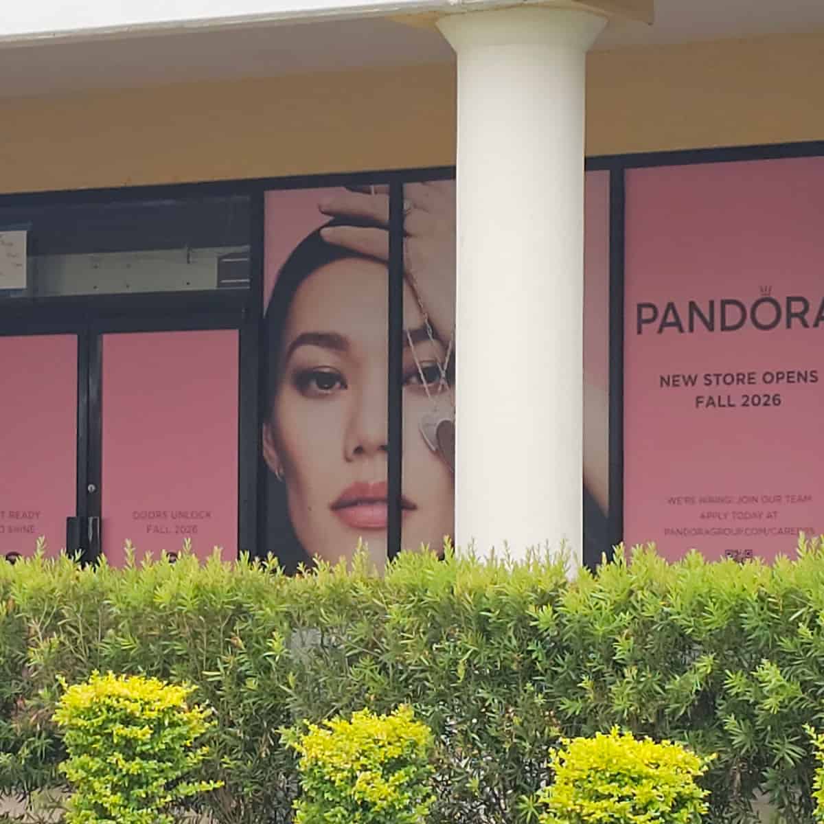 Pandora New Store opens Fall 2026 sign on the window with a woman holding jewelry