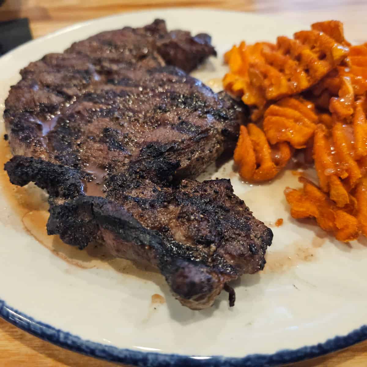 Ribeye steak on a plate with sweet potato fries