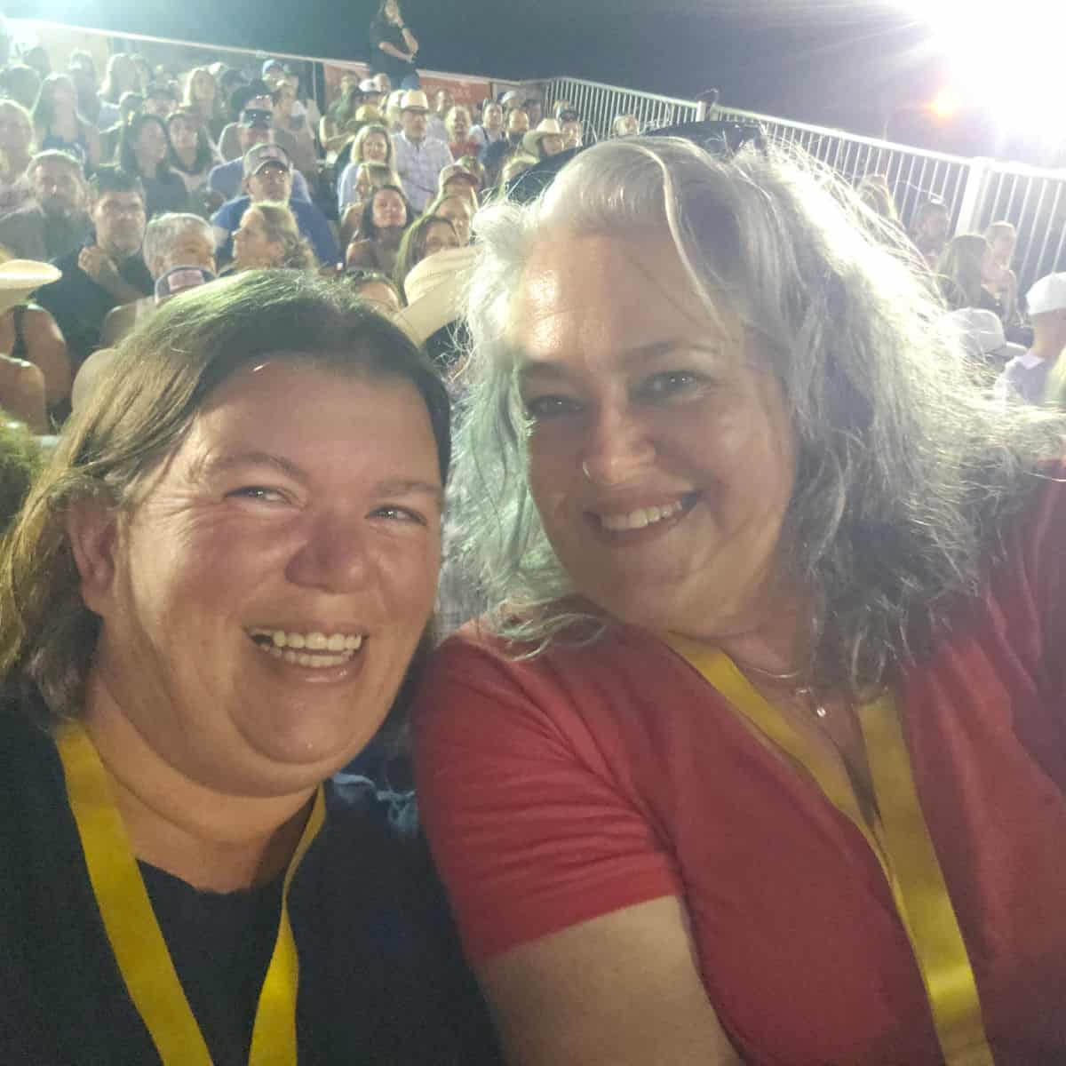 Tammilee and Brandy smiling with people in the bleachers behind them