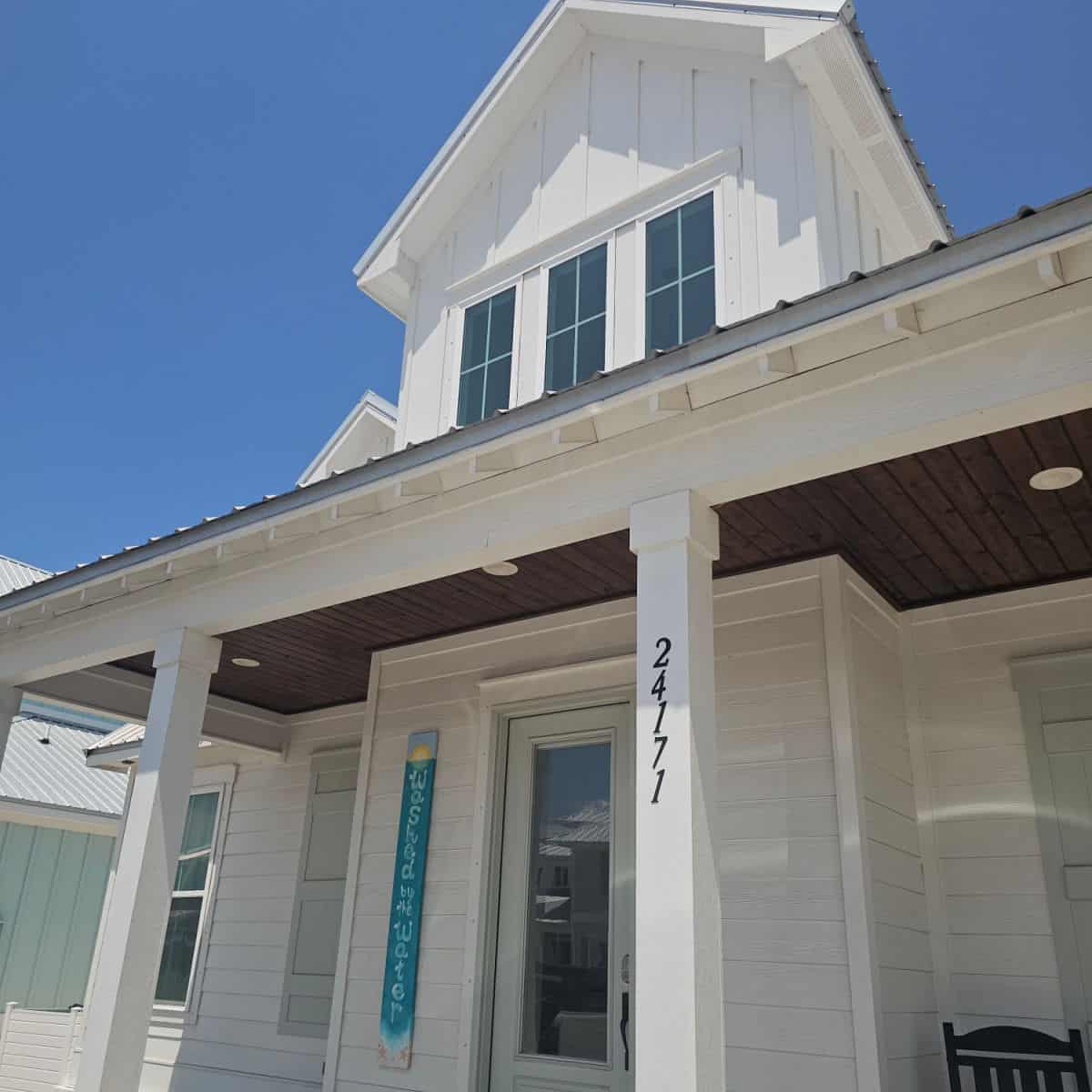 Two story white house with Washed by the Water sign