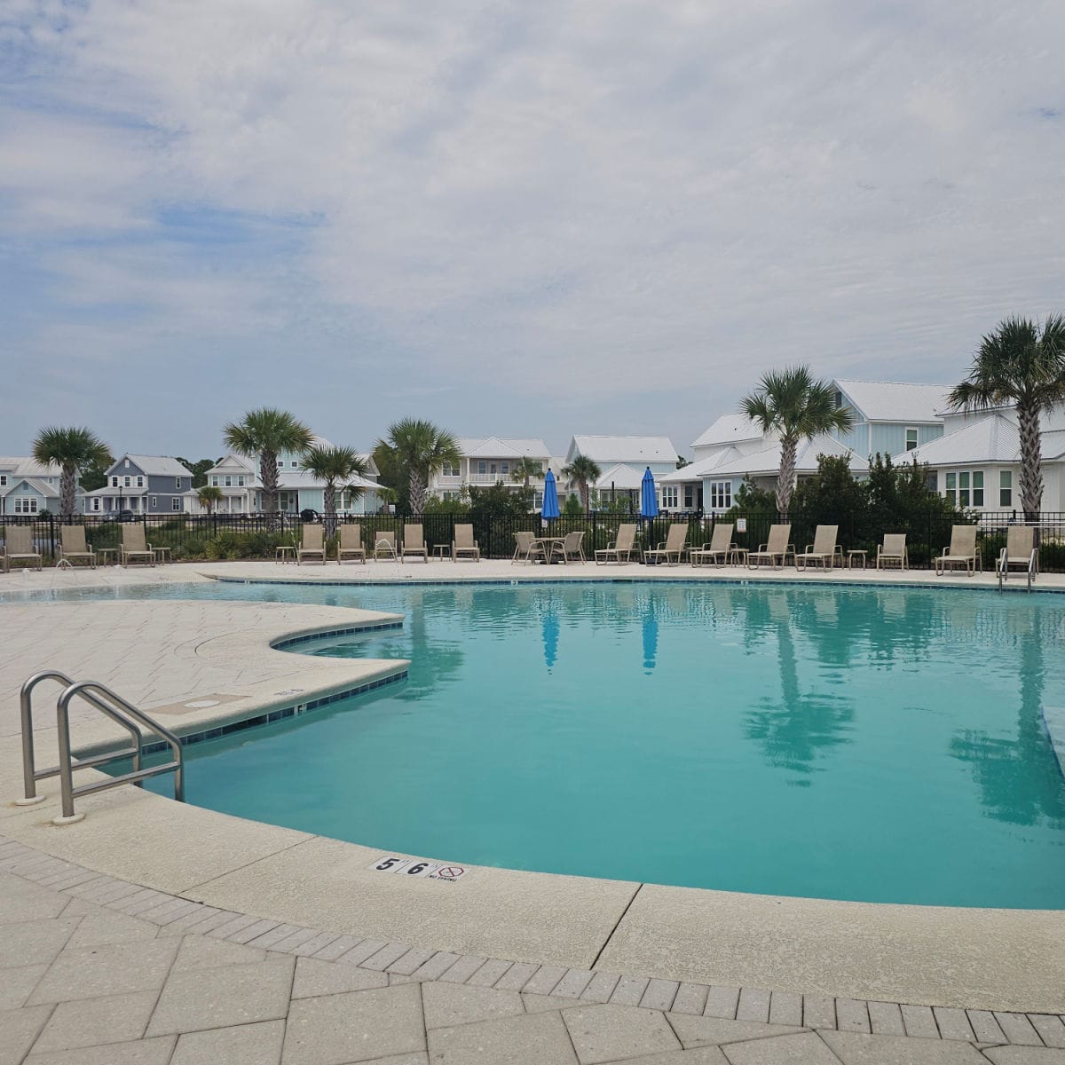 Zero entry pool with lounge chairs around the deck, vacation houses in the background