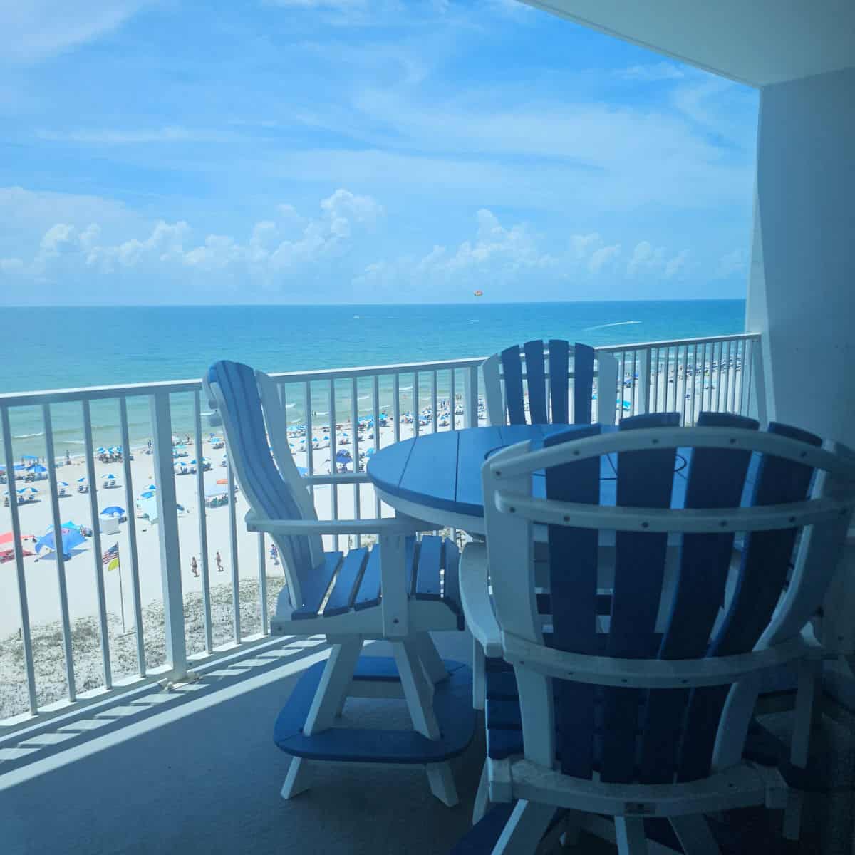 Balcony with blue chairs and a table looking out over the Gulf waters.