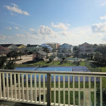 Looking over the balcony to the tennis court and outdoor pool with colorful houses