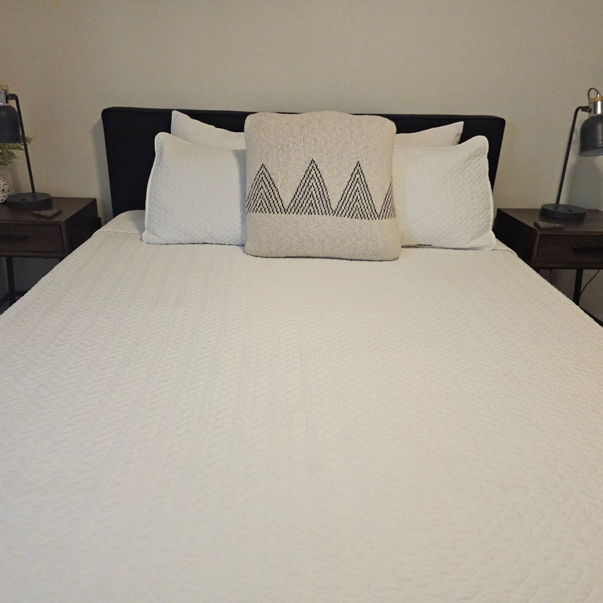 Bedroom with white linen covered bed with two nightstands with lamps