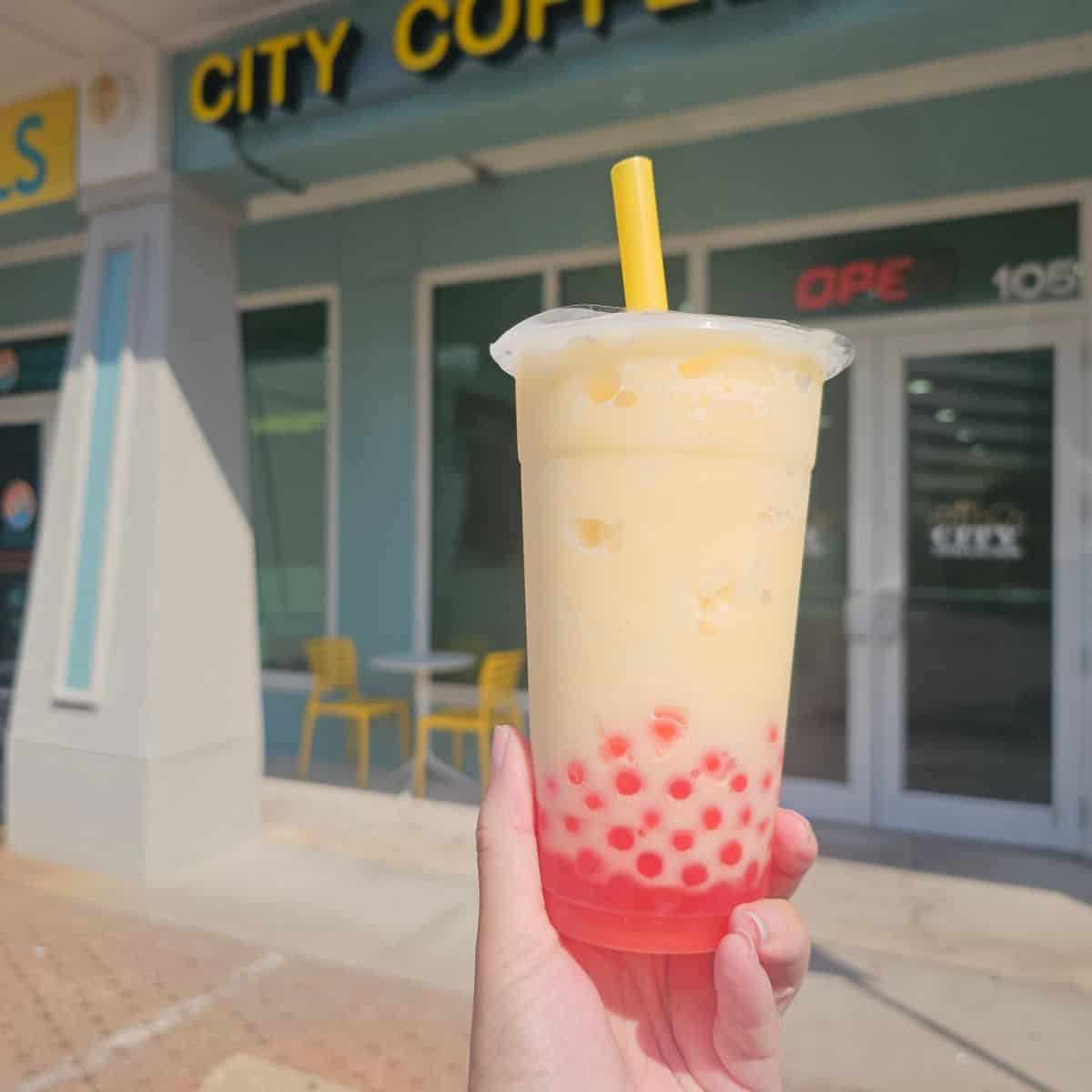 hand holding a slushy with red boba on the bottom