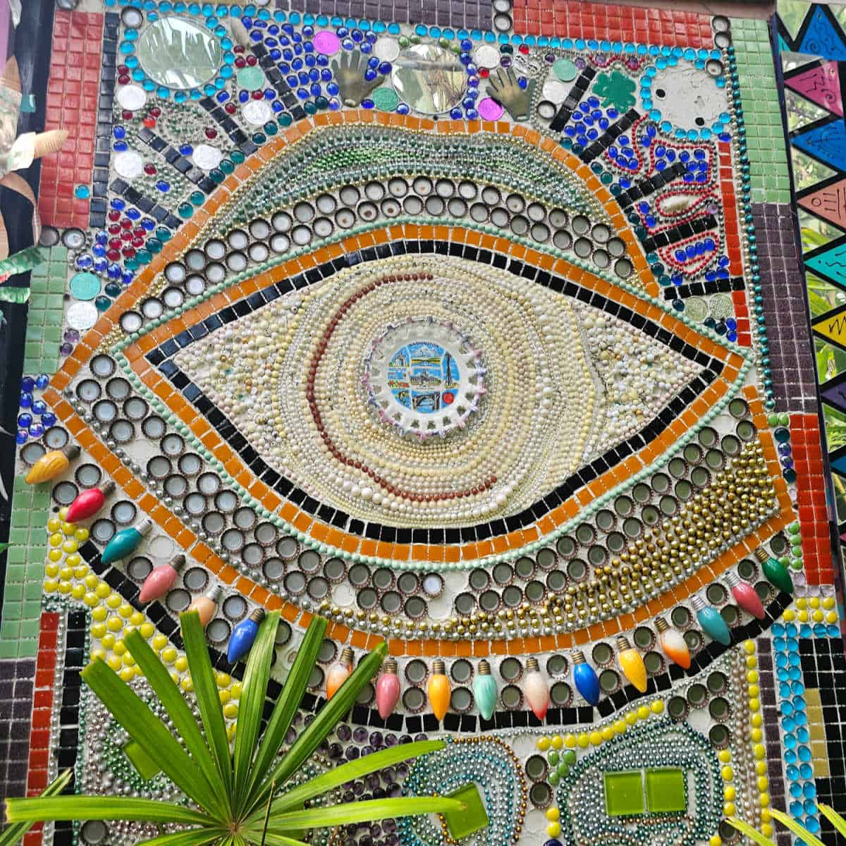 colorful eye art made with lightbulbs, bottle tops, marbles, and other colorful items