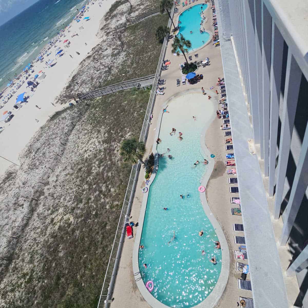 looking down over two zero entry pools next to the sand dunes and beach with Gulf waters in the background