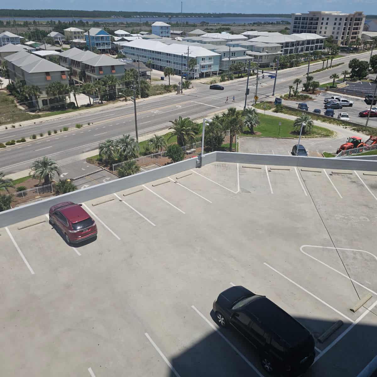 top level of the parking deck with a couple of cars looking out over Gulf shores and East Beach Bvld.