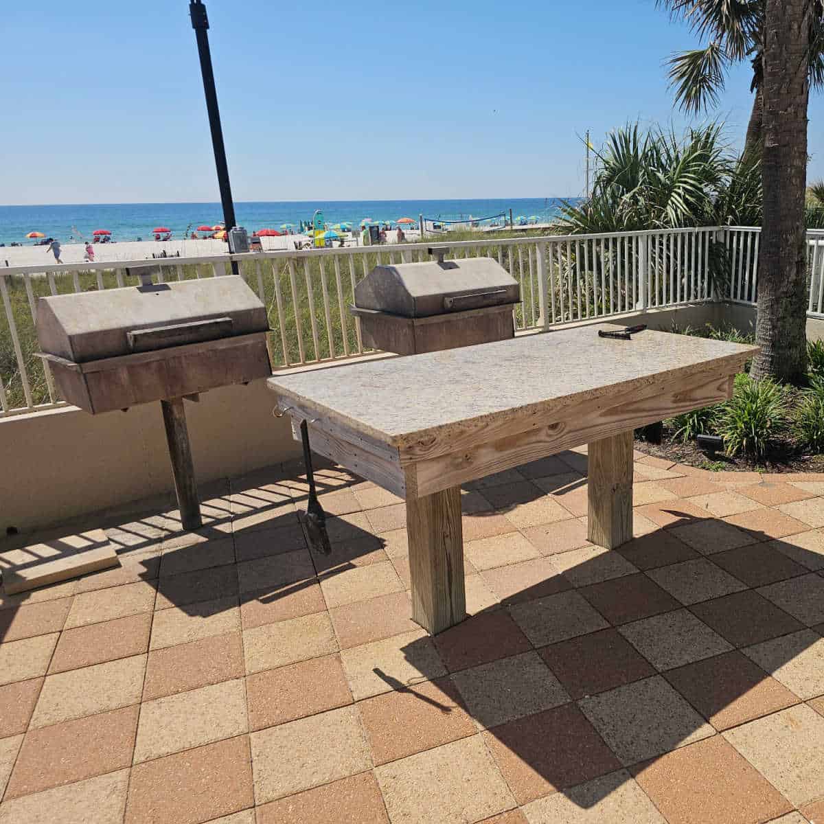 prep table near two barbecues and a fence looking out towards the beach and Gulf waters