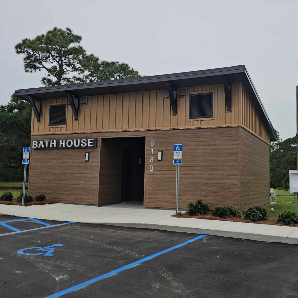 bath house sign on a brown building with accessible parking spaces in front of it