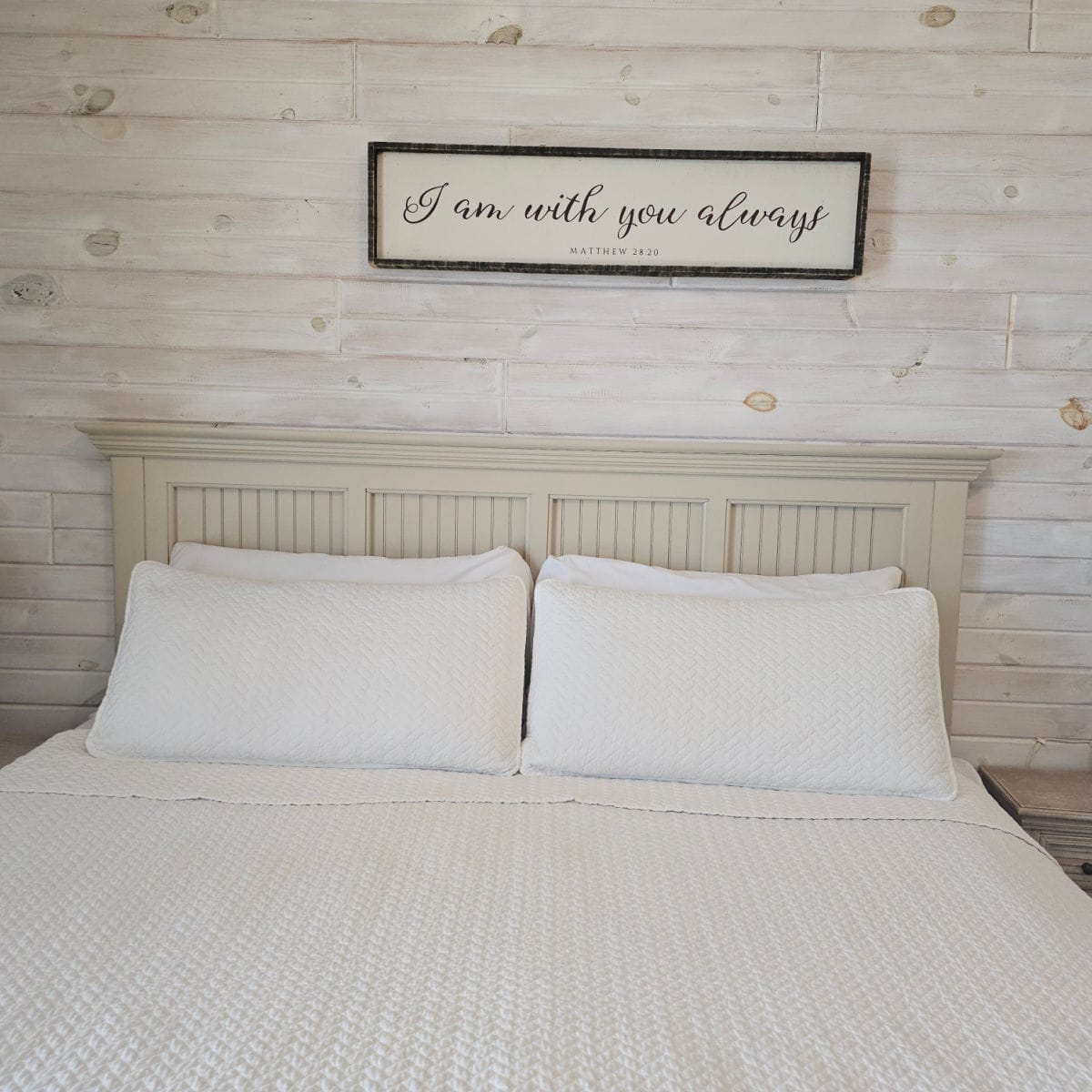 Bedroom with white wooden headboard, white lines, shiplap wall and quote on the wall