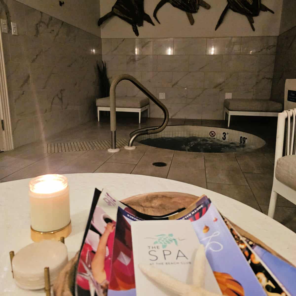 relaxation room with a hot tub, turtles on the wall, The spa at the Beach Club brochure next to a candle