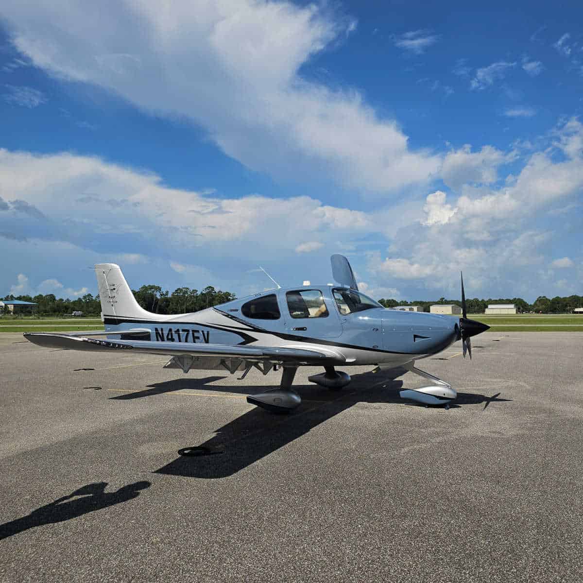Blue and white plane with a propeller on a sunny day with some clouds