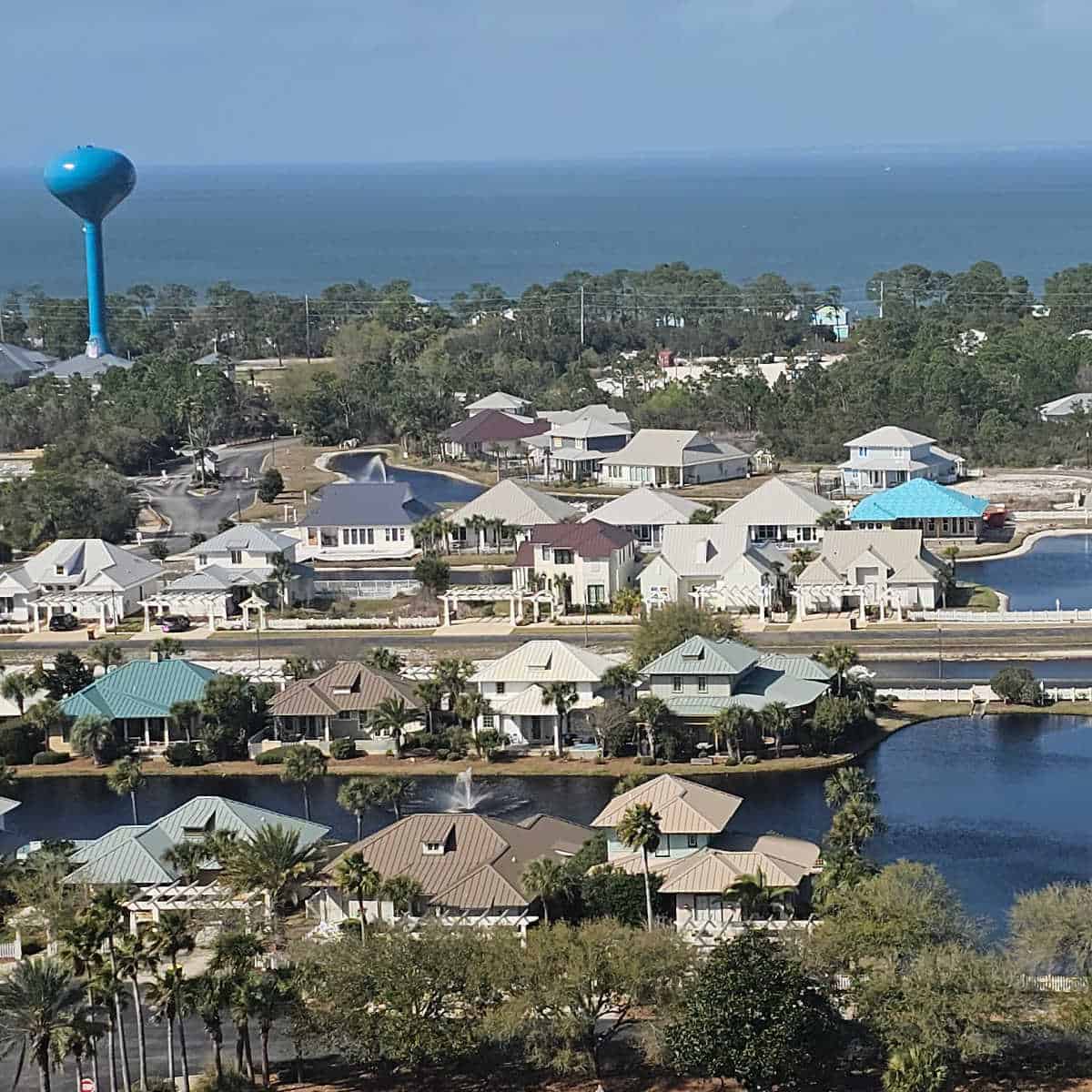 looking over the beach Club Cottages with lakes in between the rows, and the iconic turquoise water tower in the background looking towards Mobile Bay