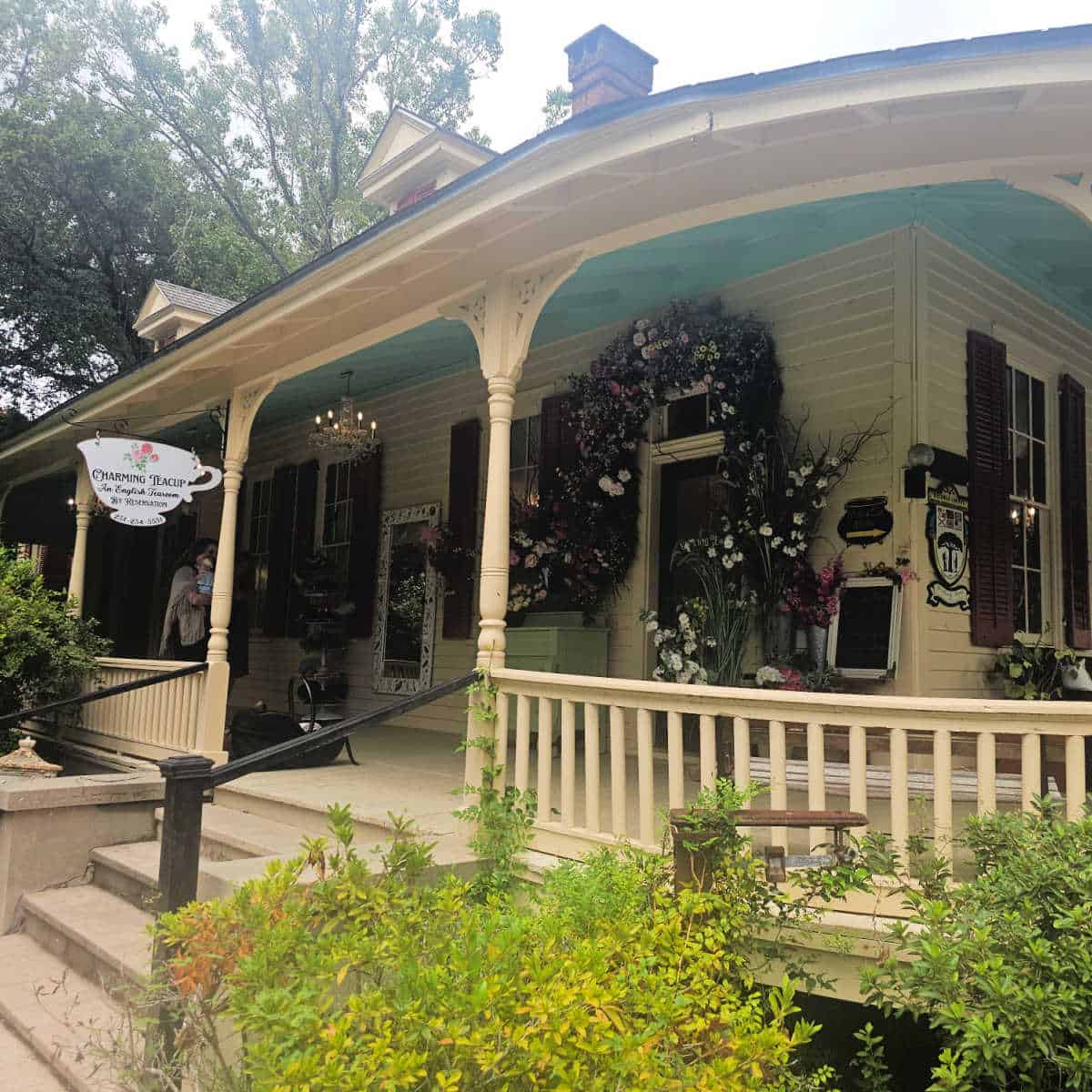 Charming Teacup exterior with steps leading up to the porch, flowers all over the walls of the porch