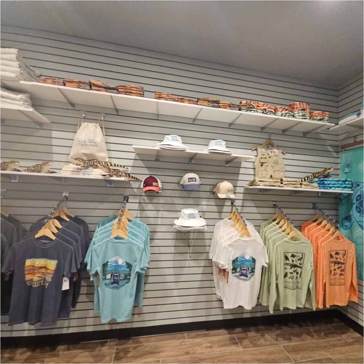 gift shop with gulf state park t-shirts, hats, bags, and towels on shelves and hanging