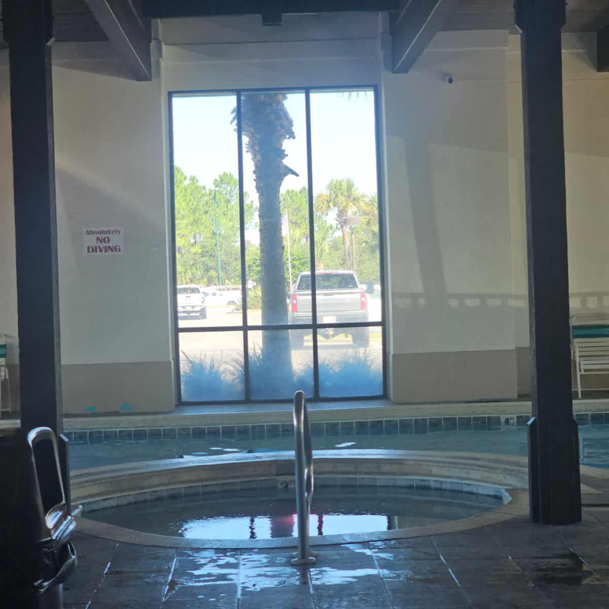 hot tub and indoor pool with a window looking out towards the parking area