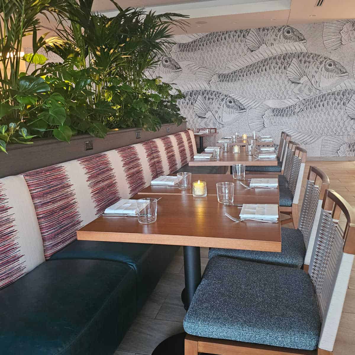 indoor seating with a long red and white bench, tables, and chairs with a large fish mural on the wall