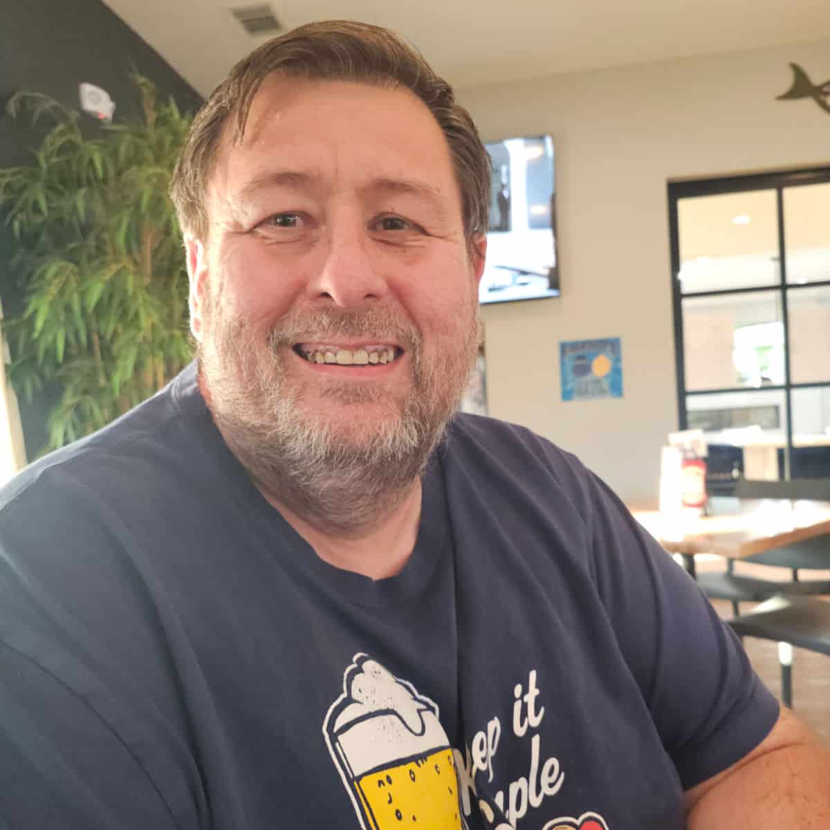 John smiling with a plant and restaurant behind him