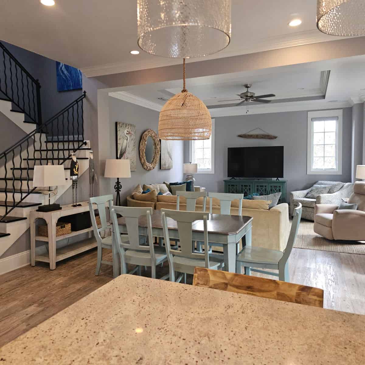 Living room with dining room table, chandelier over the table, living room with multiple chairs, wrap around couch and flatscreen tv