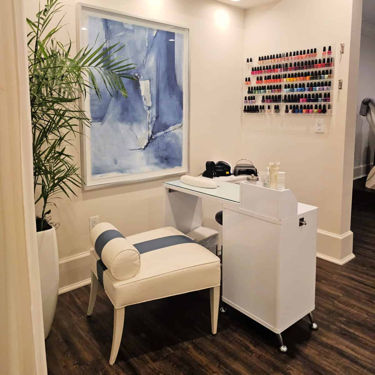 manicure station with wall of nail polish, comfortable chair and white manicure desk