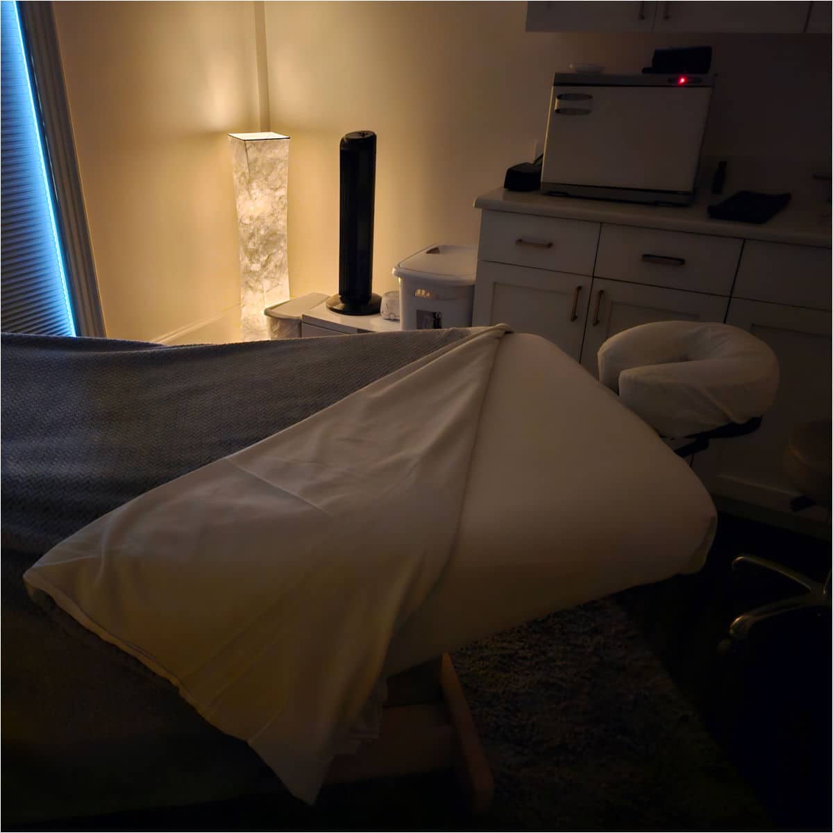 massage table with a folded over blanket. lamp in the corner