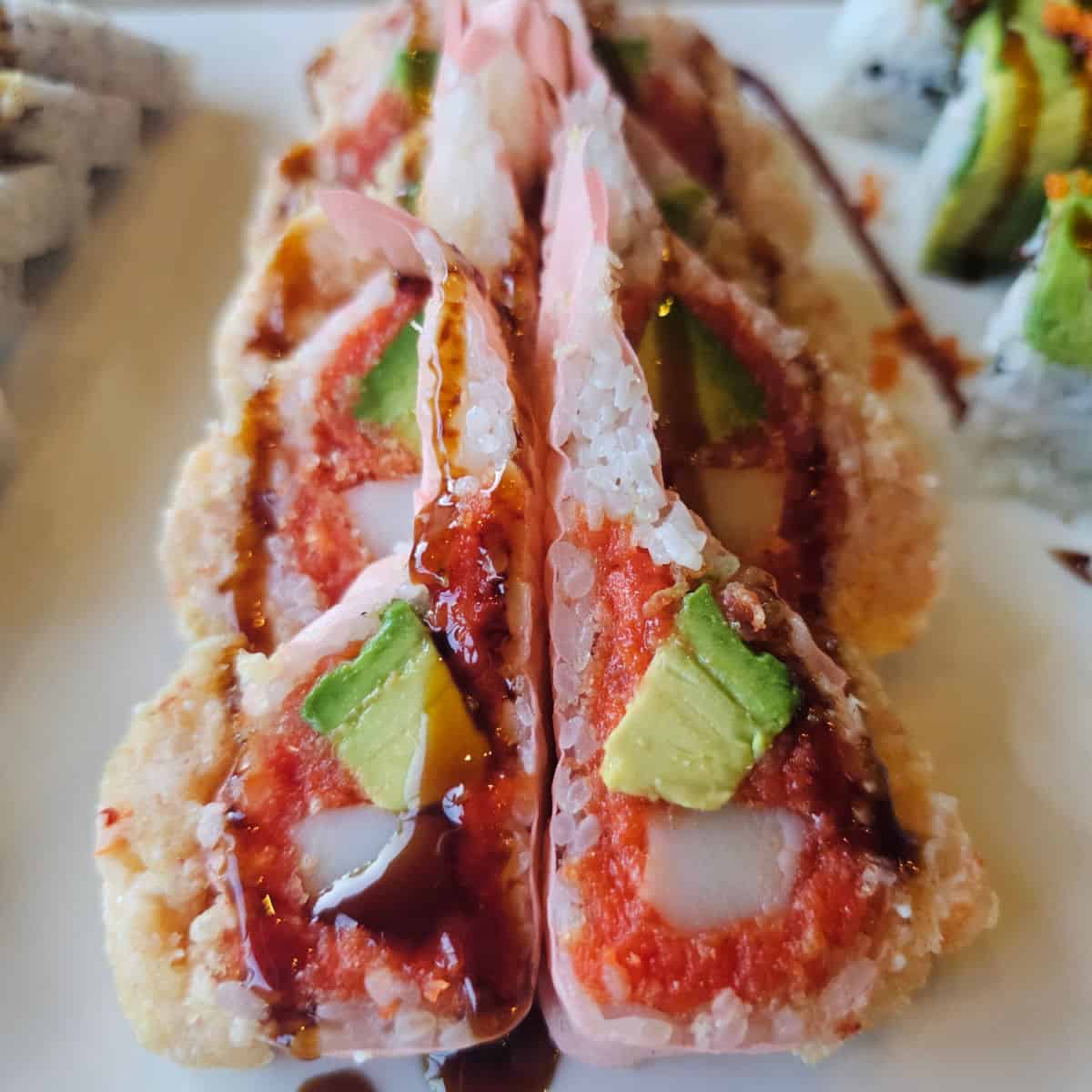 sushi roll wrapped in pink soy paper with avocado, crab, and lobster salad