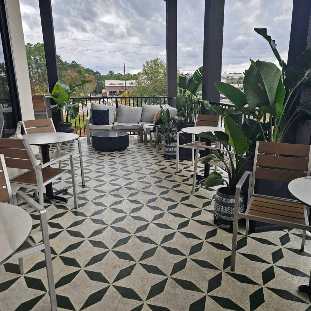 outdoor seating on a balcony with tables and chairs, a comfy couch, and plants