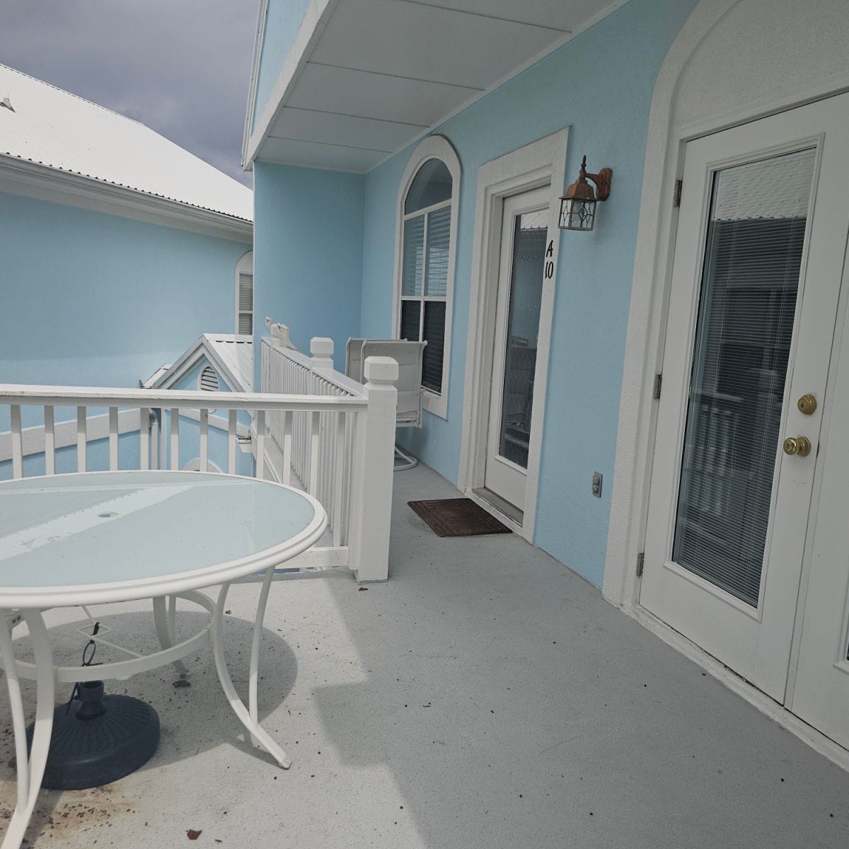 outdoor deck with the front entrance to A10, white table and chairs on the deck