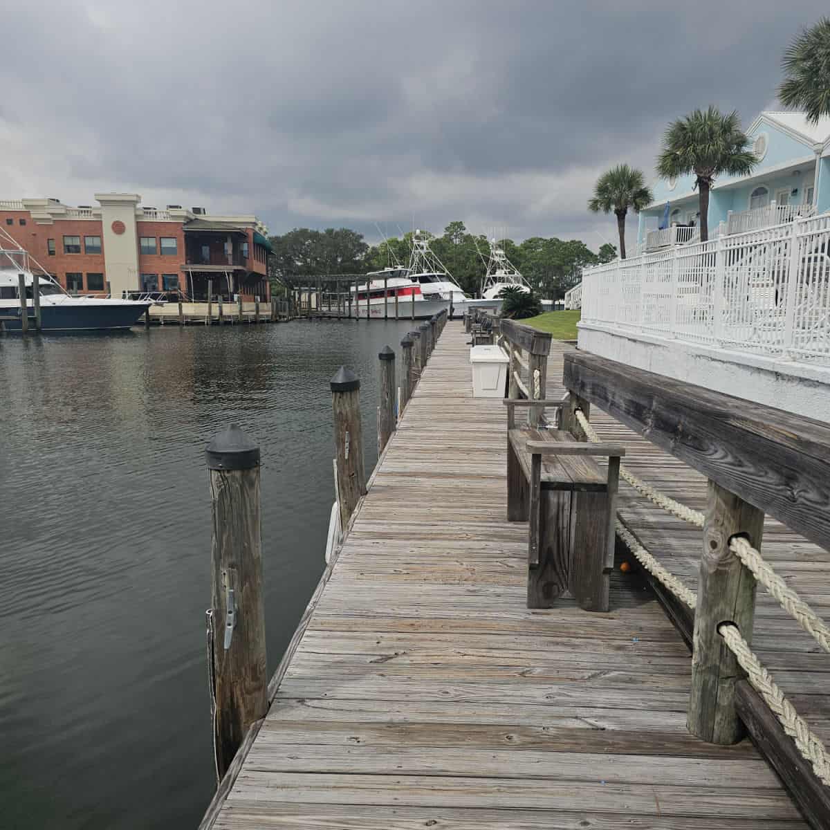 Wooden dock with Charter Landing building on the right side, buildings across the water and boats