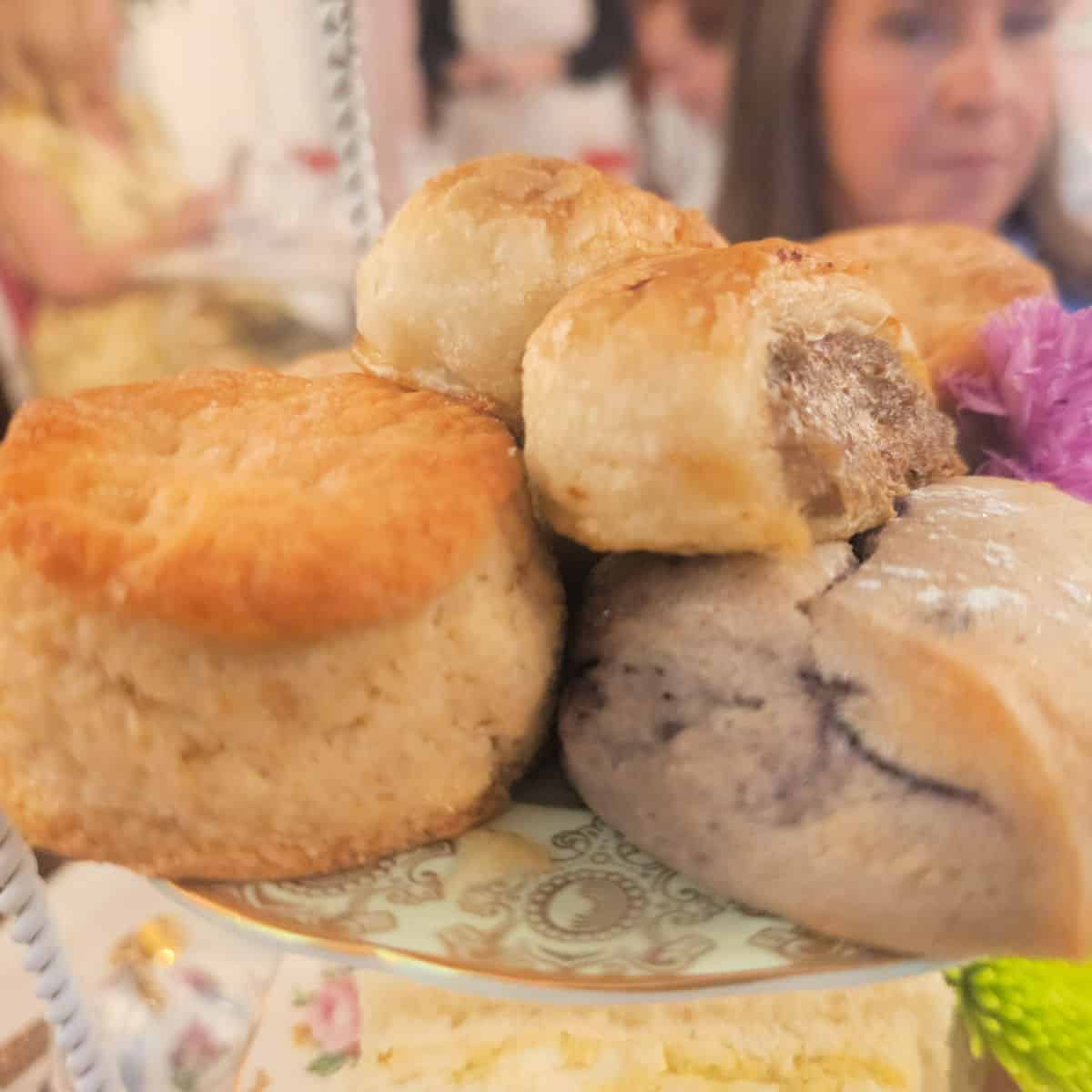 scones and English sausage roll on a colorful plate with people in the background