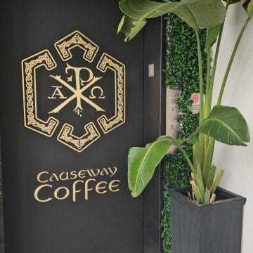Causeway Coffee logo and name on an elevator door near a plant